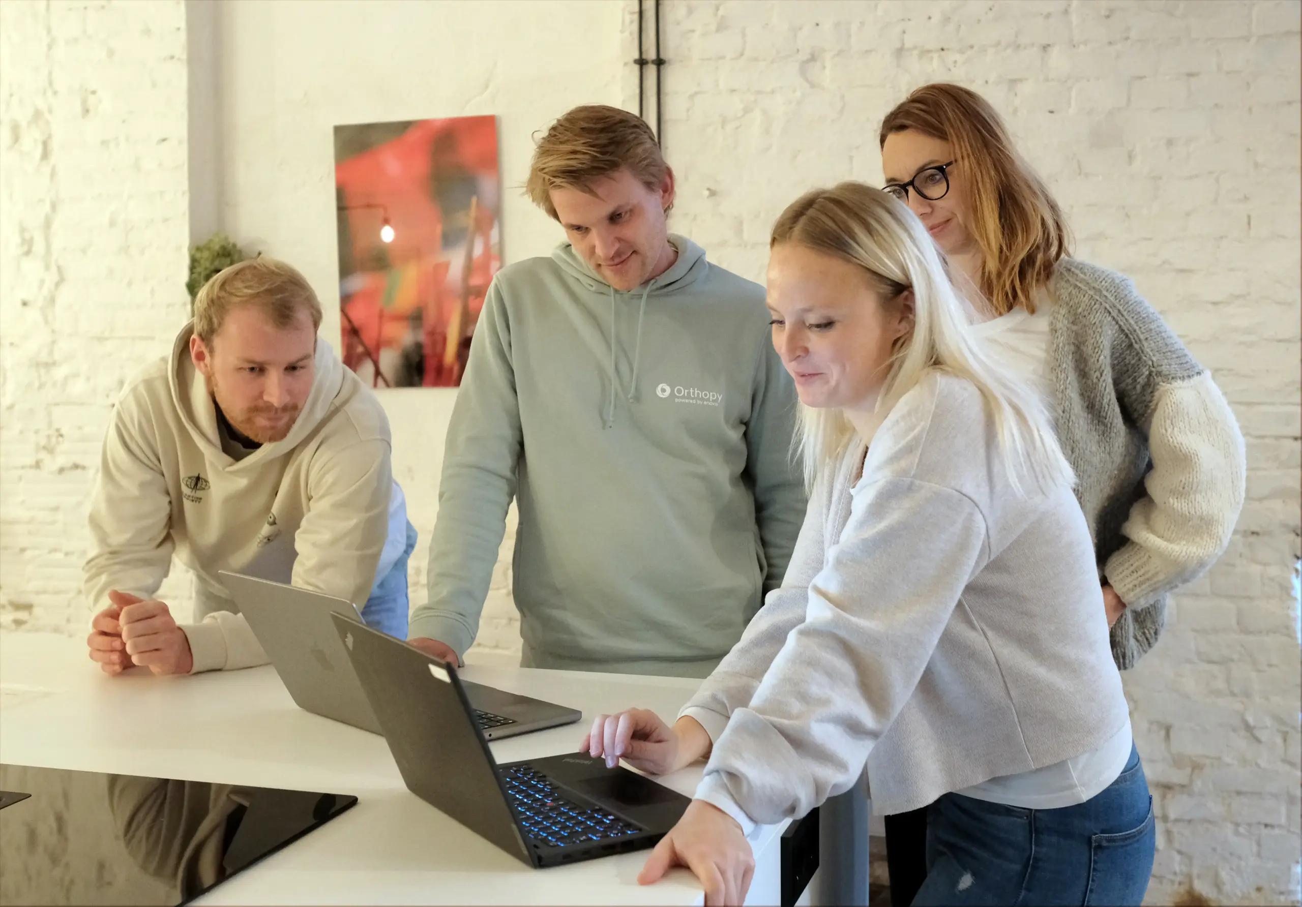 Ein Team von Mitarbeitern arbeitet fokussiert an einem Laptop, symbolisiert Zusammenarbeit und digitale Innovation.