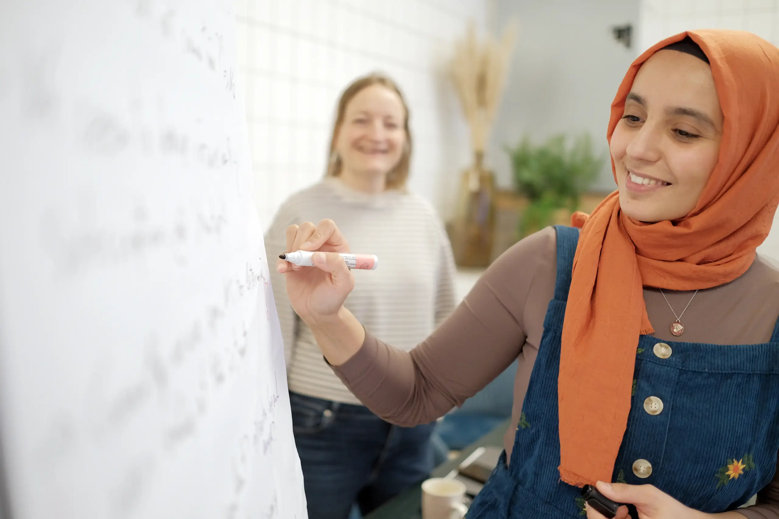 Eine Frau steht vor einem Flipchart und schreibt mit einem Marker, während sie eine Präsentation hält.